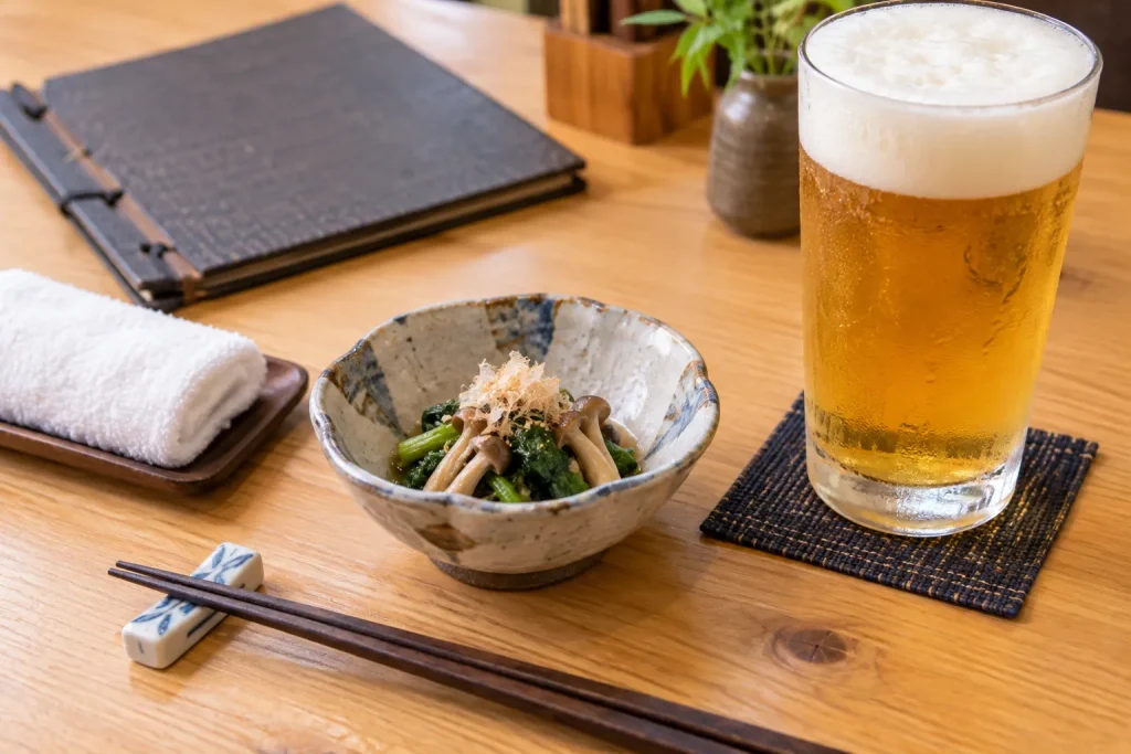 An otoshi dish beside a Japanese izakaya menu and the first drink order.