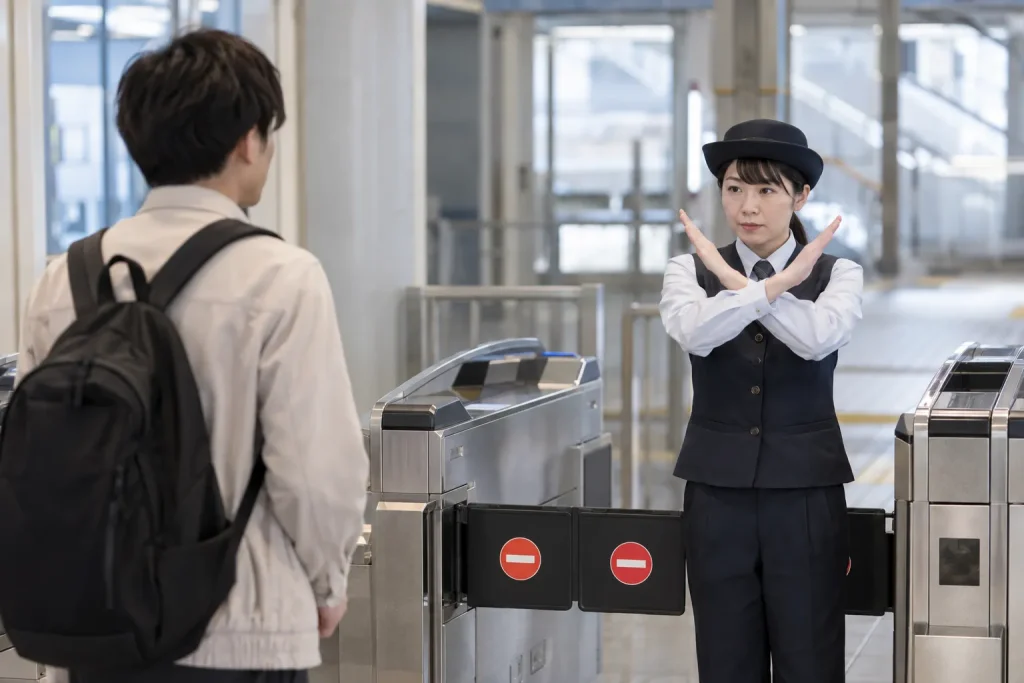 A station employee making a clear crossed-arms X near a temporarily closed entrance.