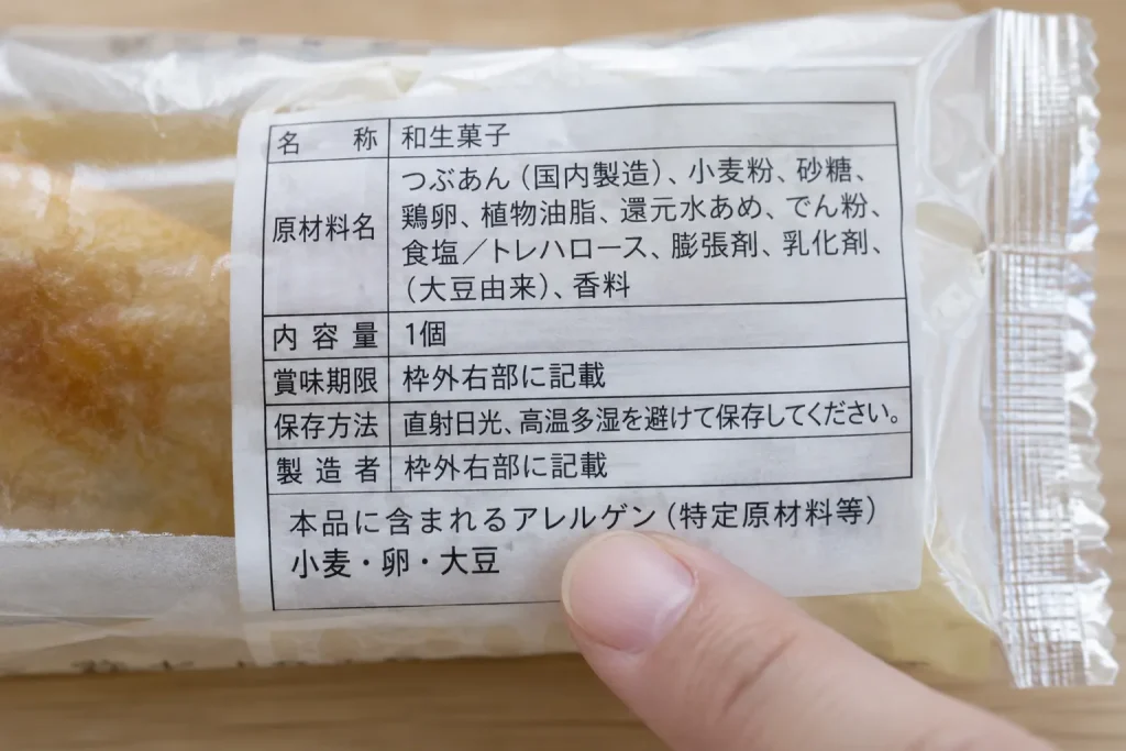 Close view of a Japanese ingredient panel with the collective allergen statement highlighted by a fingertip
