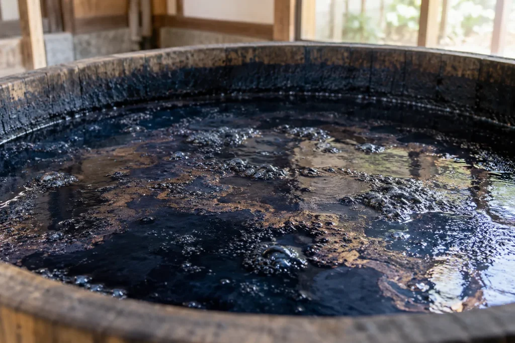 Surface of an active natural indigo fermentation vat with bubbles and the characteristic coppery film